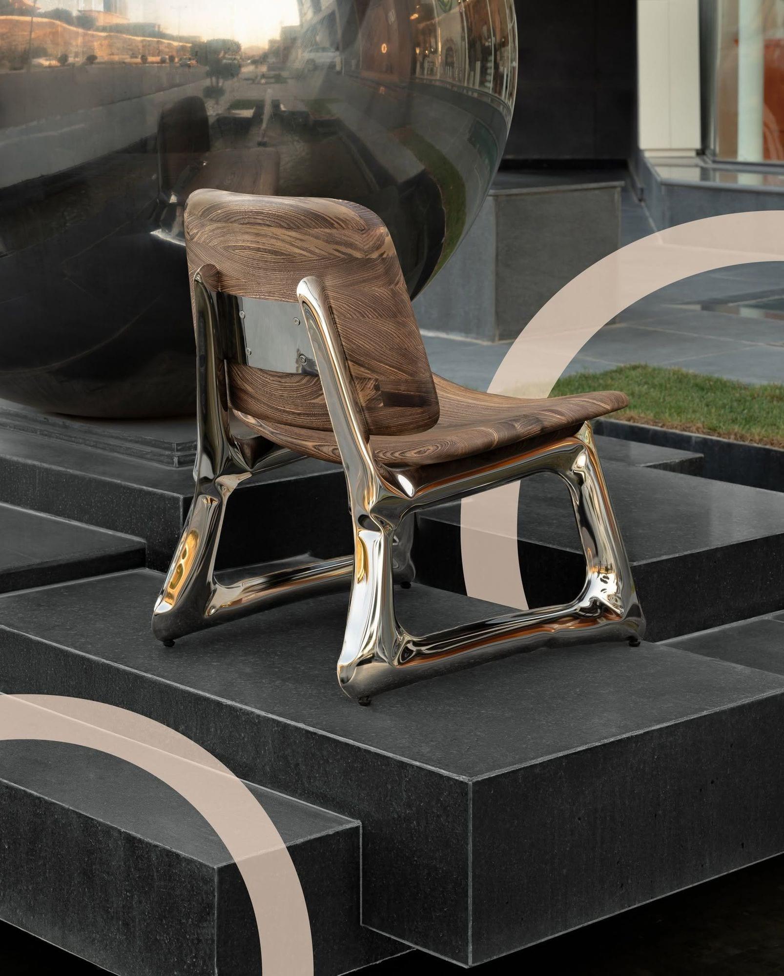 Halo Lounge Chair — walnut seat on mirror-polished steel legs, on black stone steps