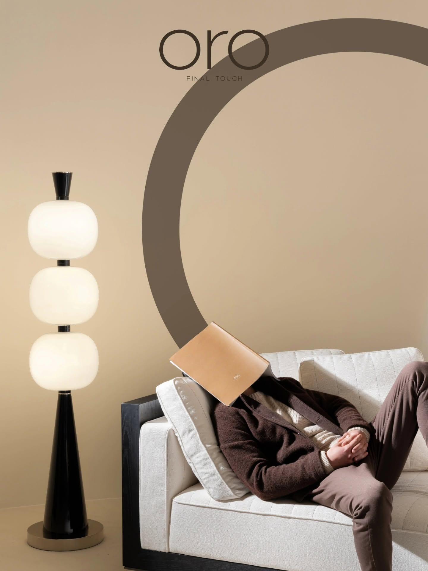 Orbit Floor Lamp — three stacked opal-glass shades on a tapered black stem, beside a white sofa